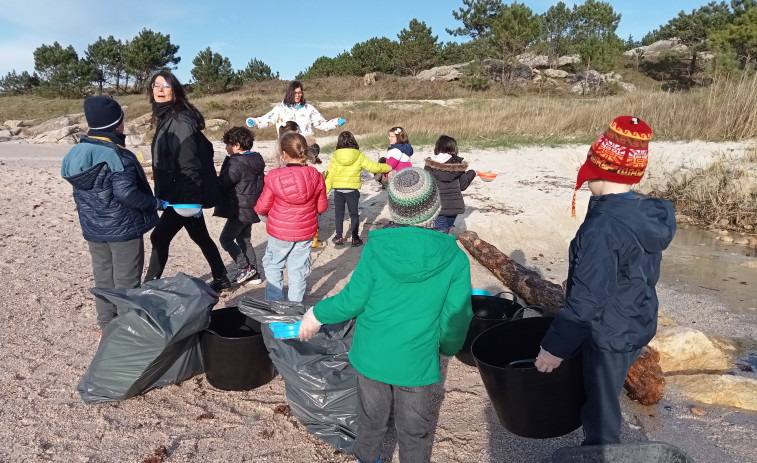 Una treintena de escolares de Aguiño se suma a la recogida de pellets plásticos en la playa de A Muralla