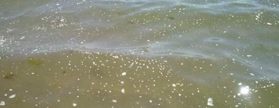 Una mancha de espuma blanca  cubre un largo tramo  de mar en A Concha