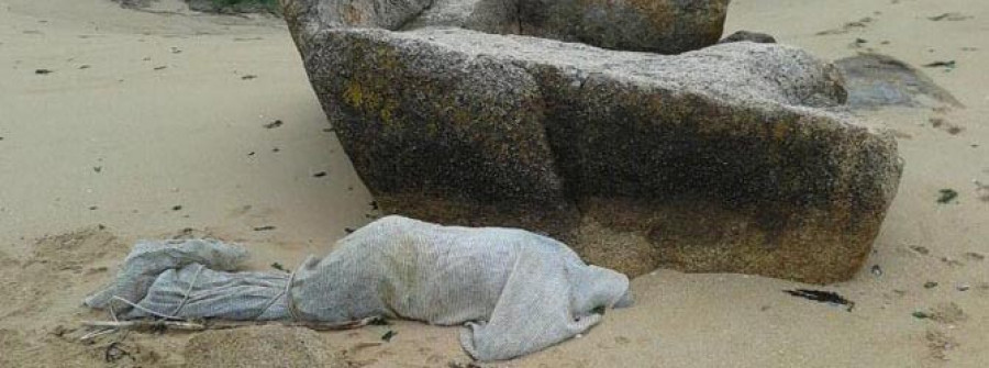 Hallan el cadáver de un hombre envuelto en una lona atada con una cuerda en A Illa
