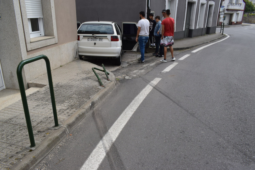 Encajado un coche entre dos casas a la entrada de una calle en Carreira