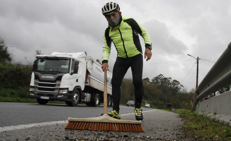 Un ciclista barre la gravilla del arcén en Bamio al considerarlo una trampa cuando va en bici