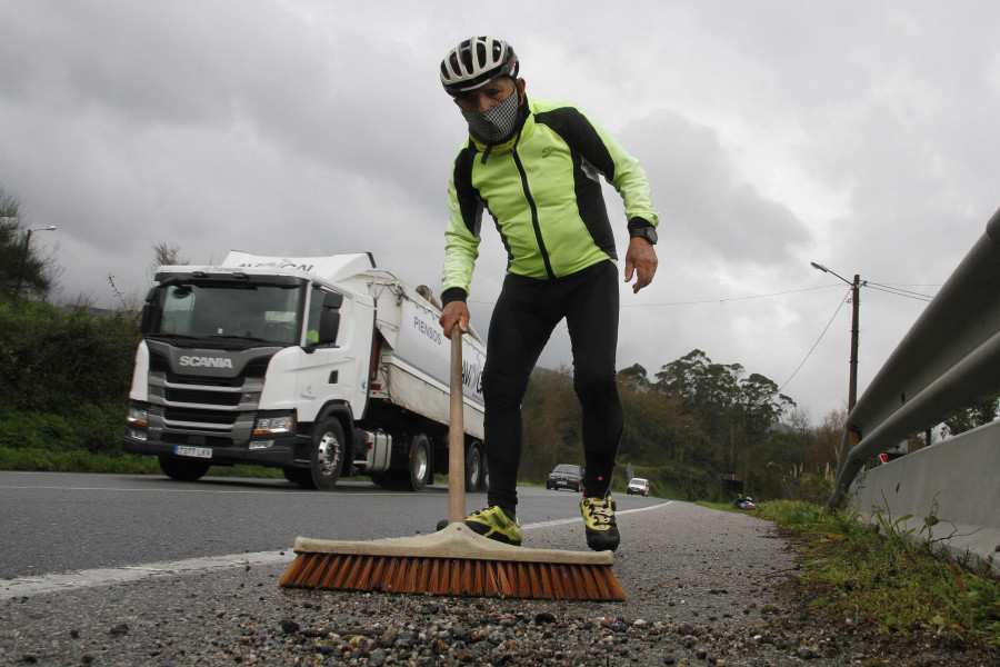 Un ciclista barre la gravilla del arcén en Bamio al considerarlo una trampa cuando va en bici