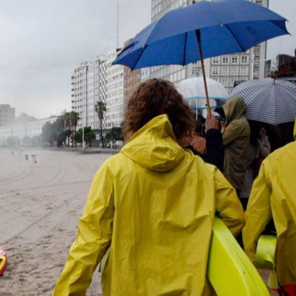 Personas con chubasquero y paraguas en la playa