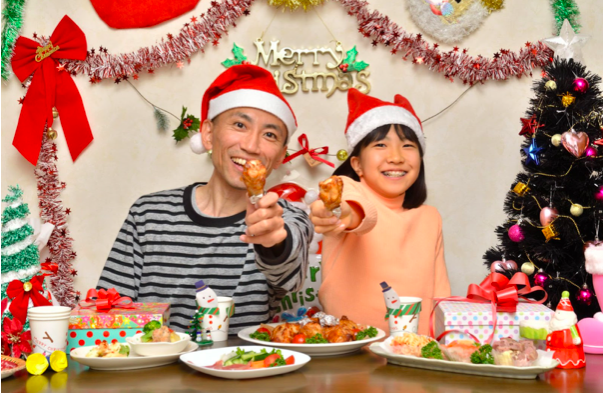  Un padre y una niu00f1a disfrutan de una fiesta de Navidad con comida de KFC. 