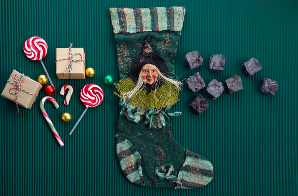 La Bruja Befana con un calcetu00edn y dulces de fondo. 