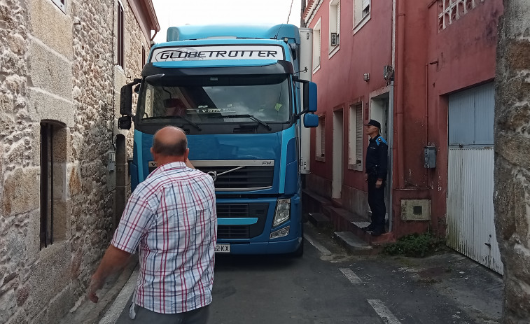 Un tráiler queda atrapado en un vial estrecho y con casas a ambas márgenes en el barrio de Deán Grande, en Ribeira