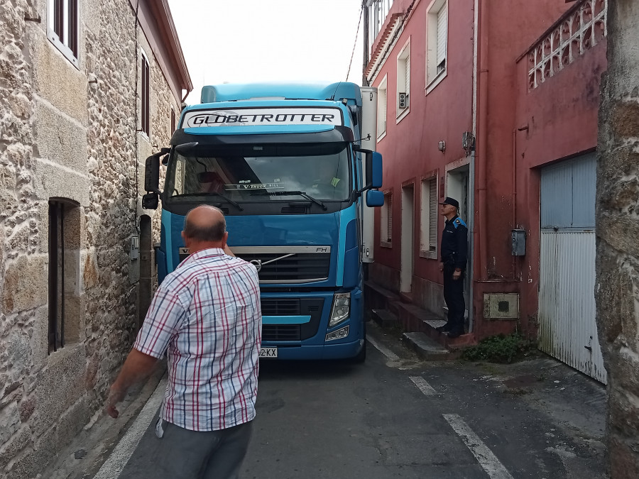 Un tráiler queda atrapado en un vial estrecho y con casas a ambas márgenes en el barrio de Deán Grande, en Ribeira