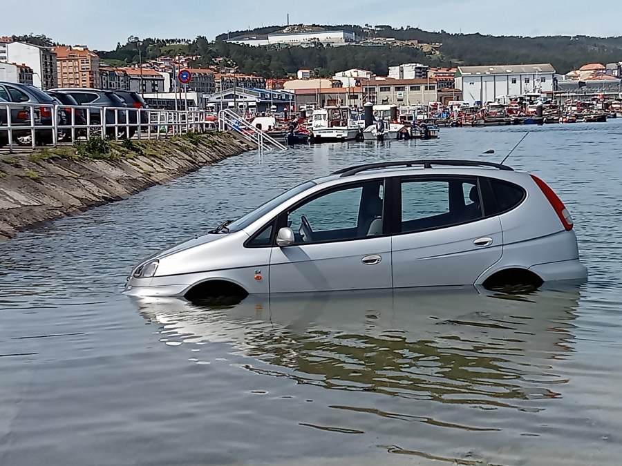 Un nuevo coche aparcado en la rampa de varada del puerto de Ribeira fue alcanzado por el agua al subir la marea